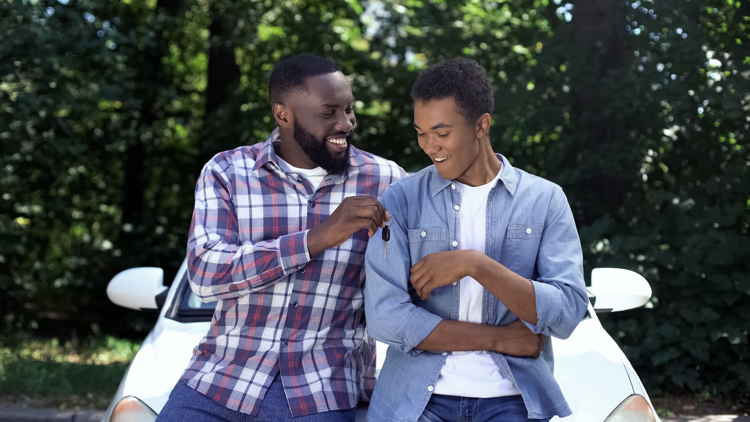 happy dad giving car key to son permission to drive